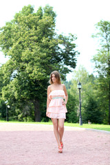 Beautiful young woman walking on the summer park