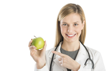 Happy Female Doctor Pointing At Green Apple