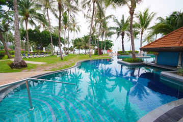 Swimming pool beside the sea with coconut tree.