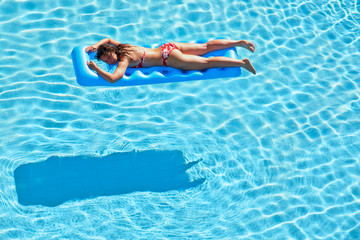 Young woman in red swimsuit bakes lying on inflatable mattress