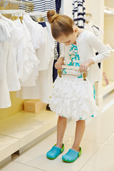 Little girl tries on short white skirt in clothing store