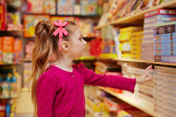 Little girl stretches to shelf with table games