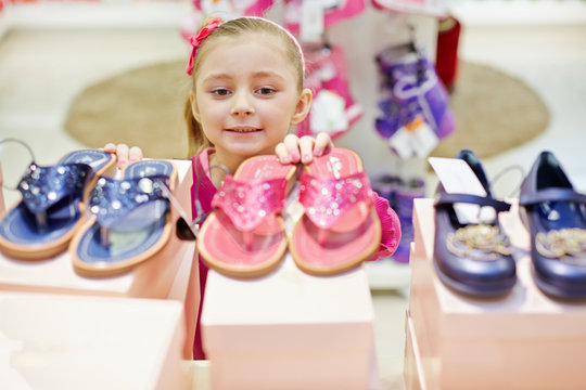 Little girl looks up on toeless shoes that stands on top of shoe