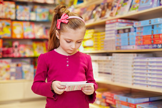Little girl views envelopes in book department of store