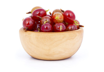 fresh red gooseberries in a wooden bowl, over a white background