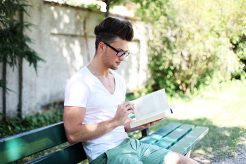 Fototapeta premium hübscher Junge ließt ein Buch im Park