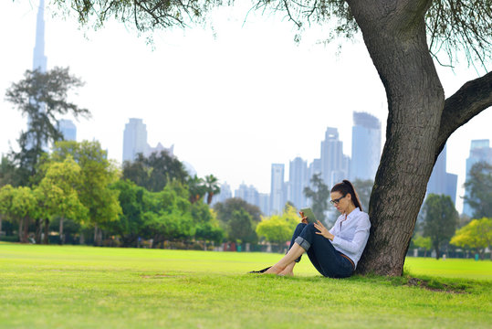 Beautiful young woman with  tablet in park - Powered by Adobe