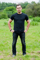 Man in a black t-shirt stands on the grass