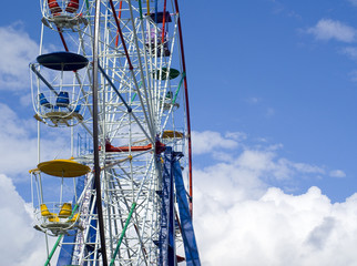 Ferris wheel in cloudy blue sky
