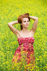 Young beautiful woman in the yellow rape field