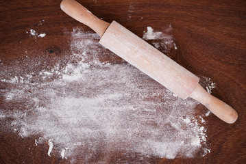 Kitchen rolling pin and flour on wooden background