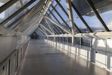 An empty pedestrian bridge at an airport is light by early morni