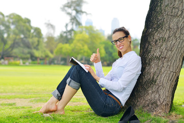 Obraz premium Young woman reading a book in the park