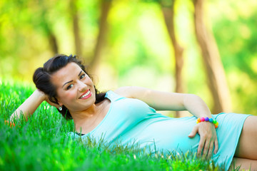 Naklejka na ściany i meble Young beautiful pregnant woman in the park