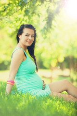 Naklejka na ściany i meble Young beautiful pregnant woman in the park