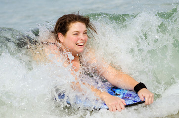Woman surfing on bodyboard at beach