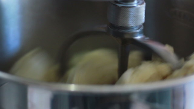 Old woman using machine to kneading dough for bread and pizza