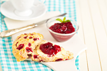 Scone with orange zest and berries with butter and jam