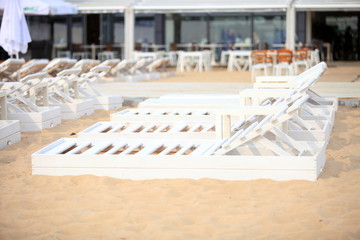 white pool chairs on sand beach