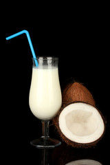 glass of coconut milk and coconuts isolated on black