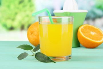 Citrus press, glass of juice and ripe orange