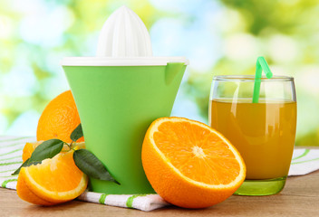 Citrus press, glass of juice and ripe oranges