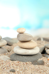 Tower of sea stones on sand on bright background