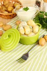Tender young potatoes with sour cream and herbs in pan