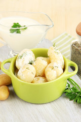 Tender young potatoes with sour cream and herbs in pan