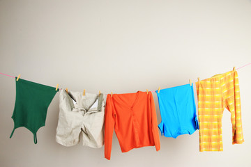 Laundry line with clothes on wall background