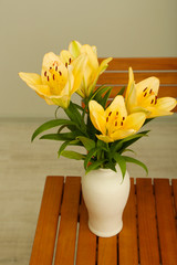 Beautiful orange lilies in vase on wooden table