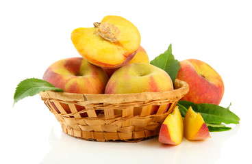 Ripe sweet peaches with leaves in basket, isolated on white