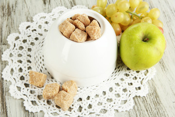 Unrefined sugar in white sugar bowl on wooden background