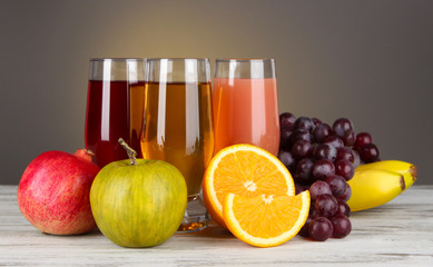 Glasses of fresh juice on table on gray background