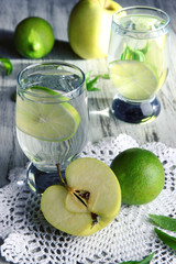 Glasses of cocktail with lime on napkin on light wooden table