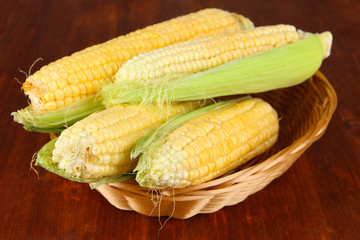 Fresh corn vegetable in wicker basket on wooden table