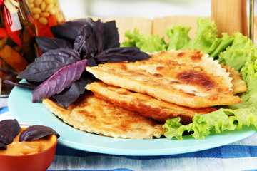 Tasty chebureks with fresh herbs on plate, close-up
