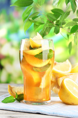 Iced tea with lemon and mint on wooden table, outdoors