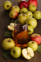 Useful apple juice with apples around on wooden table