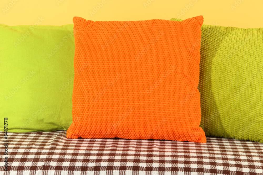 Wall mural Colorful pillows on couch on yellow background