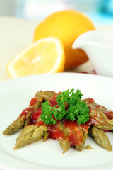 Asparagus on plate, on wooden table on bright background
