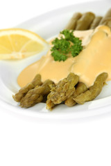 Asparagus with tasty sauce on plate, isolated on white