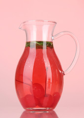 Cherry drink in pitcher on red background.