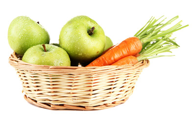 Juicy green apples and carrots with leaves in basket, isolated