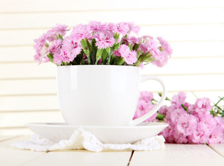 Many small pink cloves in cup on wooden background