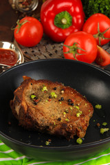 Piece of fried meat on pan on wooden table close-up