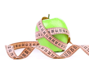 Measuring tape wrapped around a green apple.