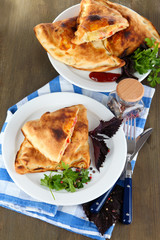Pizza calzones on plates on napkin on wooden table