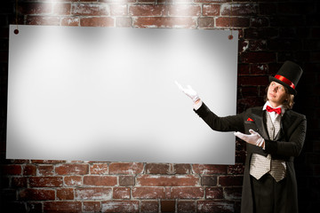 magician in top hat and tie points to the banner