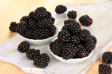 Sweet blackberry in bowls on wooden table